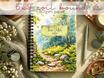 The Vital 2027 physical wellness planner featuring a watercolor forest cover, black coil binding, 6 by 9 inch size and 80 gsm interior paper. The dated spiral bound journal is displayed on a sage green desk with flowers, coffee and stationery. A compact pre-made dotted planner with monthly calendars, weekly spreads, wellness trackers, self-care activities and coloring pages.